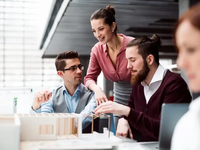 Professionals collaborate on a small model in a bright office, showcasing services listed on CityDirectoryList